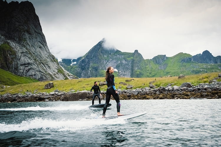 Radinn_2_WEB.jpg Two people standing on jetboards on water with mountains in the background