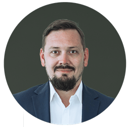 Pawel_circle.png a man wearing a suit and tie smiling and looking at the camera